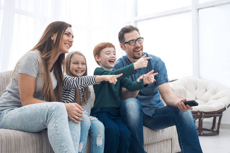 幸福的家庭坐在看电视在他们的家