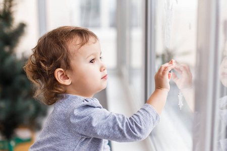 可爱的小三年女孩透过窗户看节日装饰。圣诞节和新年窗户装饰
