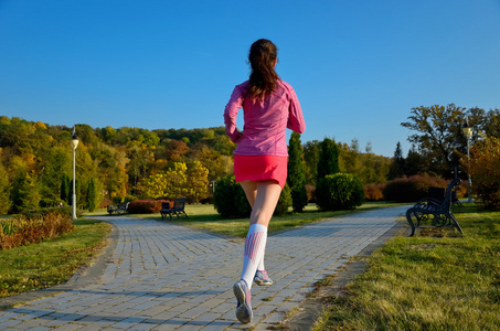 在秋天公园，美丽的女孩跑慢跑在户外跑步的女人