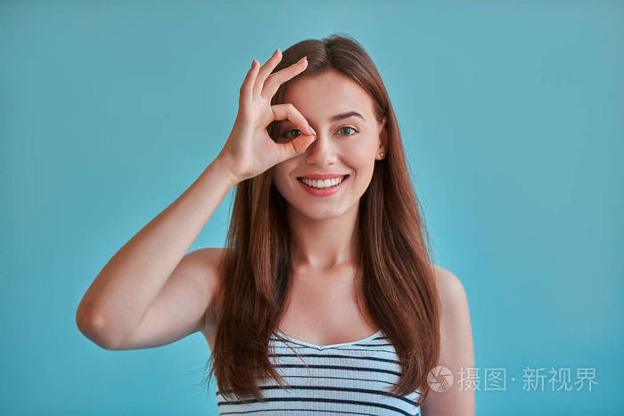 快乐女孩的肖像摆姿势, 微笑和显示 ok 标志照片-正版商用图片0a631w