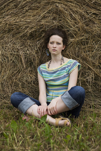 女孩坐在干草堆附近