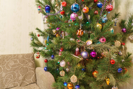 在带沙发的客厅内部, 用许多五颜六色的玩具装饰着绿色的大节日圣诞树。美丽的新年背景与文本的空间