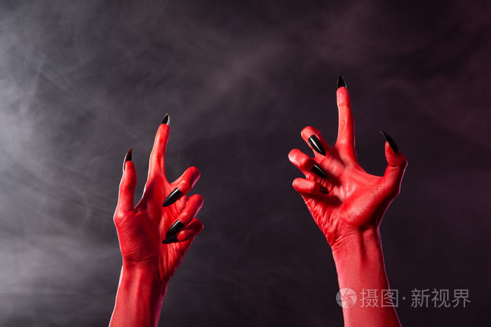 黑色的尖指甲好的令人毛骨悚然的红魔鬼手照片-正版