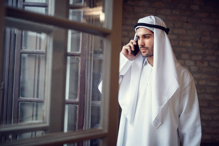 年轻的阿拉伯商人谈论手机在公司