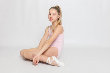 一个小可爱的年轻芭蕾舞演员在家里的地板上芭蕾姿势和伸展练习