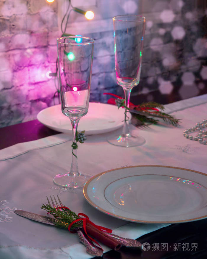 照片 在节日服务的桌子上放了两个空的香槟酒杯, 旁边是盘子,叉子和刀