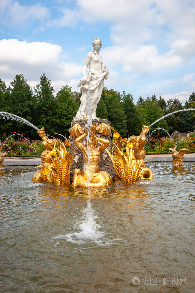 的水随地吐痰天鹅和神话般的女性希腊雕像在一个宫殿花园的雕刻喷泉