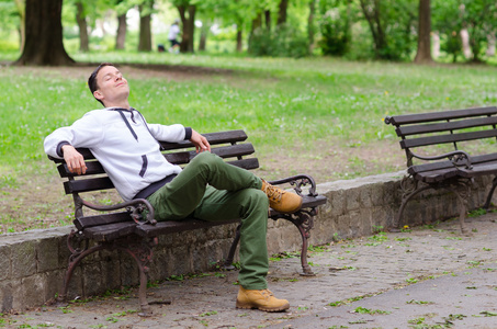 年轻人在公园的长凳上坐下来享受美丽
