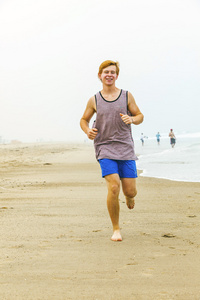 在空的海滩在早上可爱年轻十几岁的男孩 joging