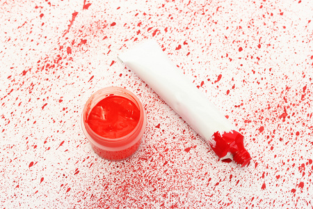 与红水粉和管与红色的喷漆特写背景上的红色水彩 jar