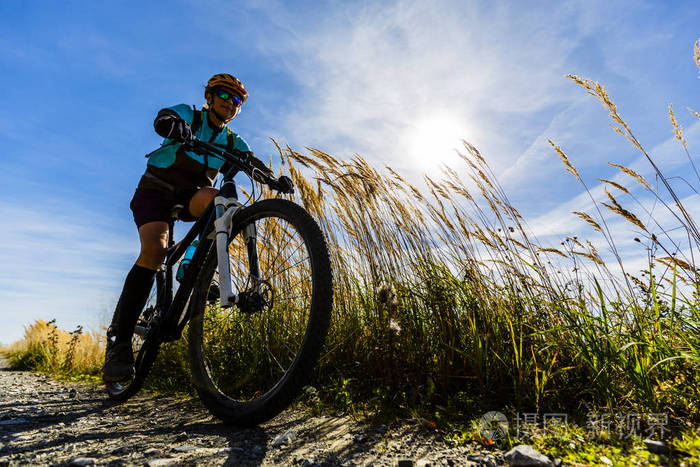 山地自行车在秋天的风景林.女子自行车山地车流动上山的小道