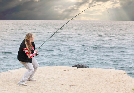 年轻女子在海岸边捉鱼