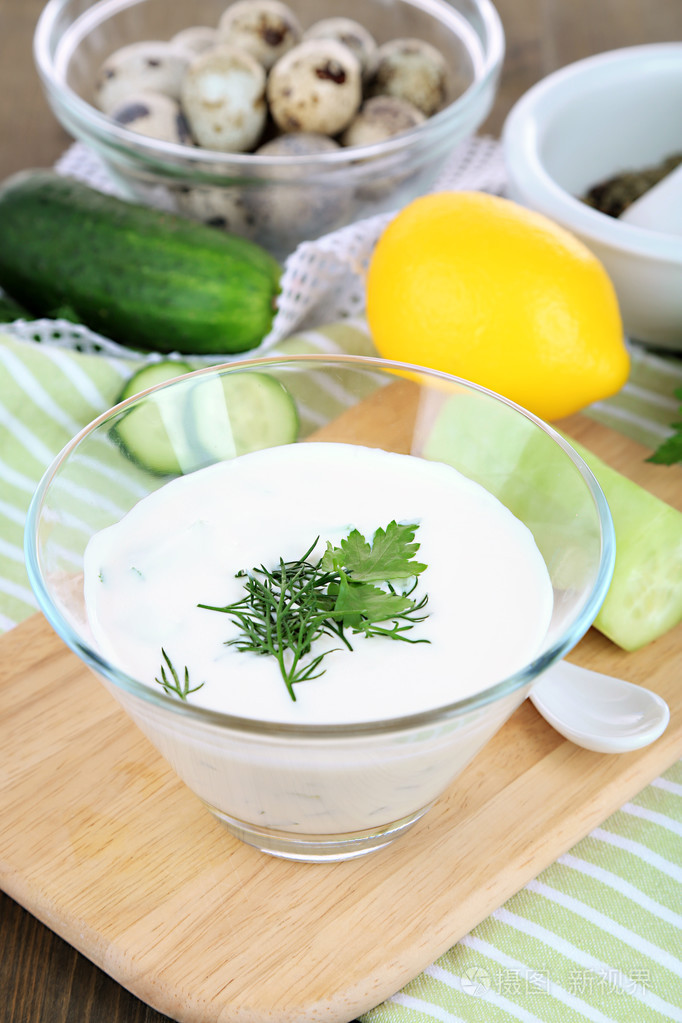 黄瓜酸奶在玻璃碗里,颜色餐巾,木制的背景上