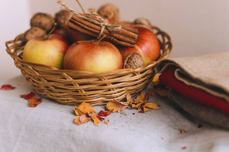 还生活在柳条篮子里的苹果布核桃花瓣和用绳子包裹的肉桂棒。秋天或冬天的家舒适的概念