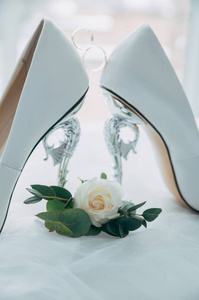 一双带戒指的白色婚纱鞋在凳子上