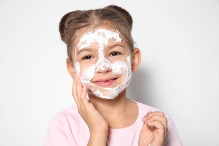 可爱的小女孩与肥皂泡沫在脸上对白色背景