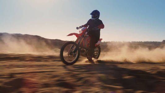 侧视图视频的专业摩托车骑手驾驶在沙丘上。它的日落和轨道覆盖着烟雾灰尘污垢。模糊运动