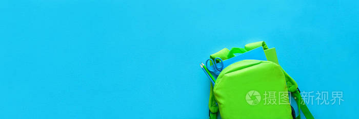 横幅31 用于 Web。回到学校的概念。绿色背包与学校用品在蓝色背景。顶部视图。复制空间