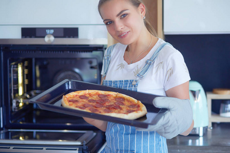 快乐的年轻女人，烹饪比萨饼在家里
