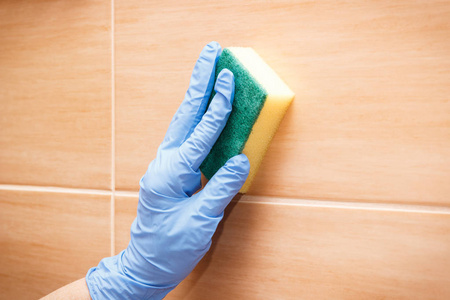 高级妇女手在防护橡胶手套洗涤和擦拭浴室瓷砖使用海绵, 家庭责任的概念