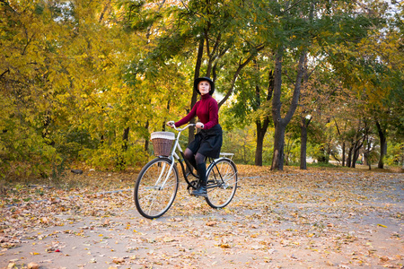 在秋天的公园里骑着复古自行车的年轻女子