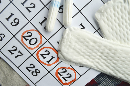 女人卫生防护，关闭 up.menstruation 日历与棉花卫生棉条，橙色格柏，卫生护垫红色背景上