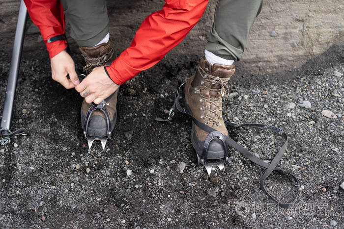 关闭裁剪照片高角度的登山人在红色防水夹克拉吊索防滑远足冰镐装置, 专注于鞋带专业靴