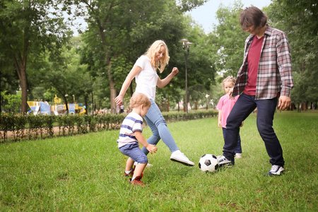 愉快的家庭在公园踢足球在夏天天