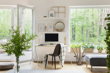 真实照片白色客厅内部与大窗口, 玻璃门, 新鲜植物, 木桌用样机计算机和简单的海报在架子上