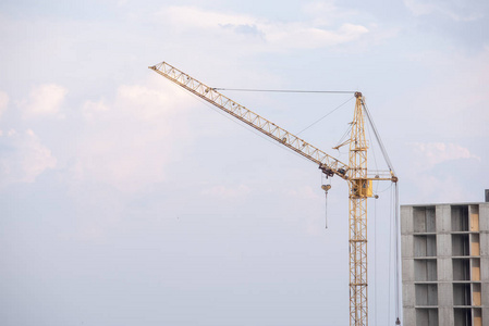 多层建筑附近天空背景下的黄色建筑起重机