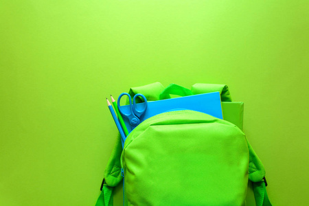 回到学校的概念。绿色背包与学校用品的绿色背景。顶部视图。复制空间