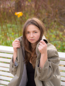 一个女孩在秋天的长凳上的肖像