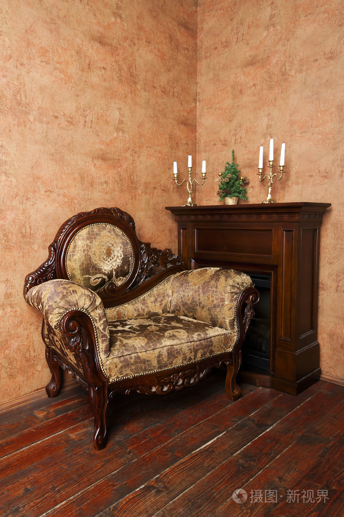 旧的老式室内豪华扶手椅, 壁炉, 烛台和小圣诞树