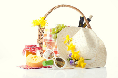 野餐篮带瓶红酒 水果 面包和夏天的帽子上白色孤立