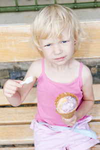 坐在长凳上的冰淇淋的小女孩
