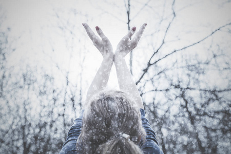 女孩用手在空中期待季节的第一雪