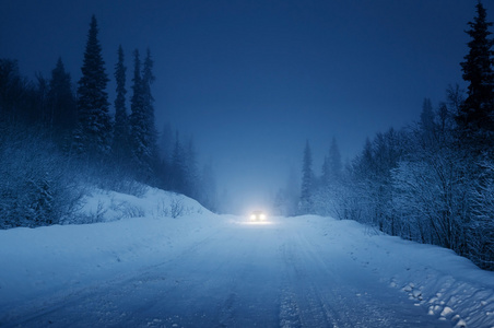 汽车和冬季路在森林里的灯光