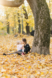 年轻的母亲与美丽的女儿正在公园散步在金色的秋天。玩得开心, 笑, 拍自拍