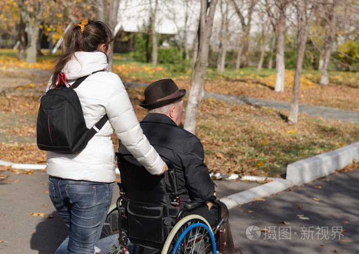 一位老人推着轮椅上的女人