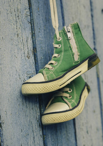 一对二手绿色纺织鞋挂在蓝色背景, 特写