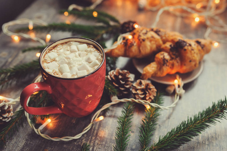 棉花糖和羊角面包与圣诞灯仿古木制的桌子上的热可可。舒适的冬天的家居理念