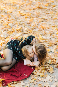 年轻的母亲与美丽的女儿正在公园散步在金色的秋天。玩得开心, 笑, 拍自拍