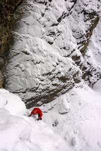 在瑞士阿尔卑斯山, 在被陡峭的雪覆盖的冰盖上, 穿着红色夹克的登山者
