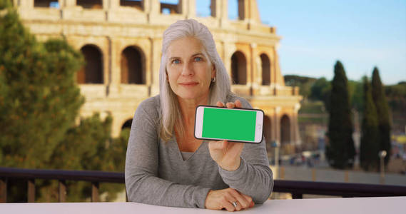 在罗马斗兽场附近的智能手机上展示年轻克里的老年白人女性