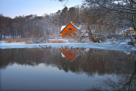 美丽的孤独的房子在湖岸边在森林 mirroing 湖在冬天以雪天气