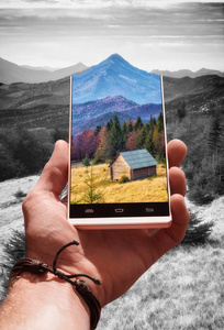 五颜六色的风景与高山谷和木房子在智能手机屏幕反对单色背景。旅行和冒险概念