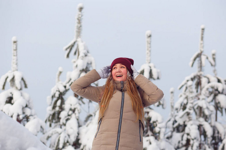 幸福的女人在美丽的雪覆盖的冷杉树。寒冷的寒假
