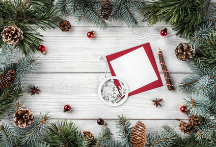 创意框架由圣诞树树枝在白色木背景与纸卡笔记, 松果, 球。圣诞节和新年主题。平面布局, 顶部视图