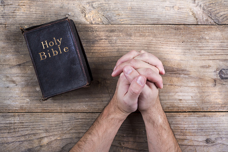 祈祷与圣经的男人的手照片