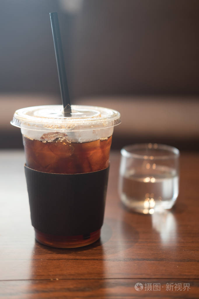 咖啡厅木桌上的冰黑咖啡塑料杯